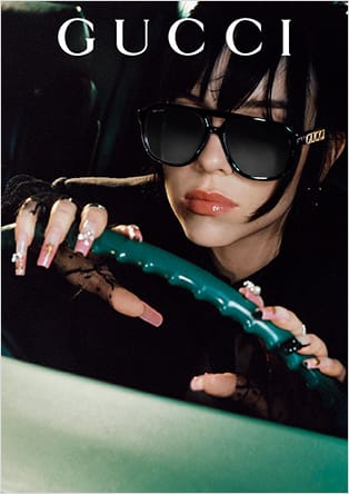 Gucci promotional image of a woman in sunglasses driving a car.