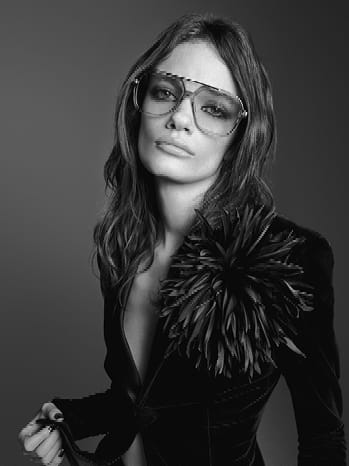 Saint Laurent promotional image of a lady in a black top wearing glasses.